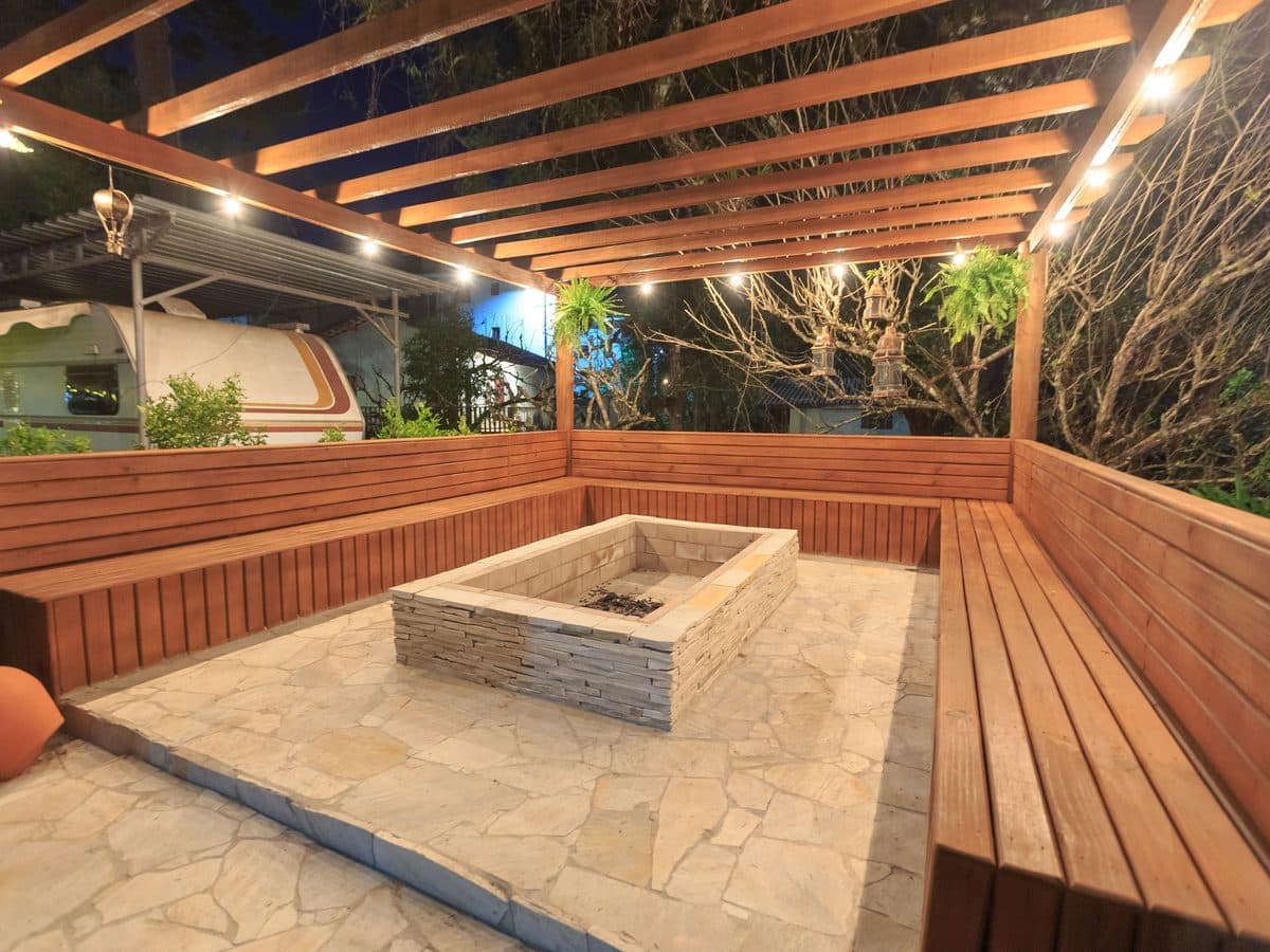 Stone fire pit surrounded by built-in bench seating on a paver terrace