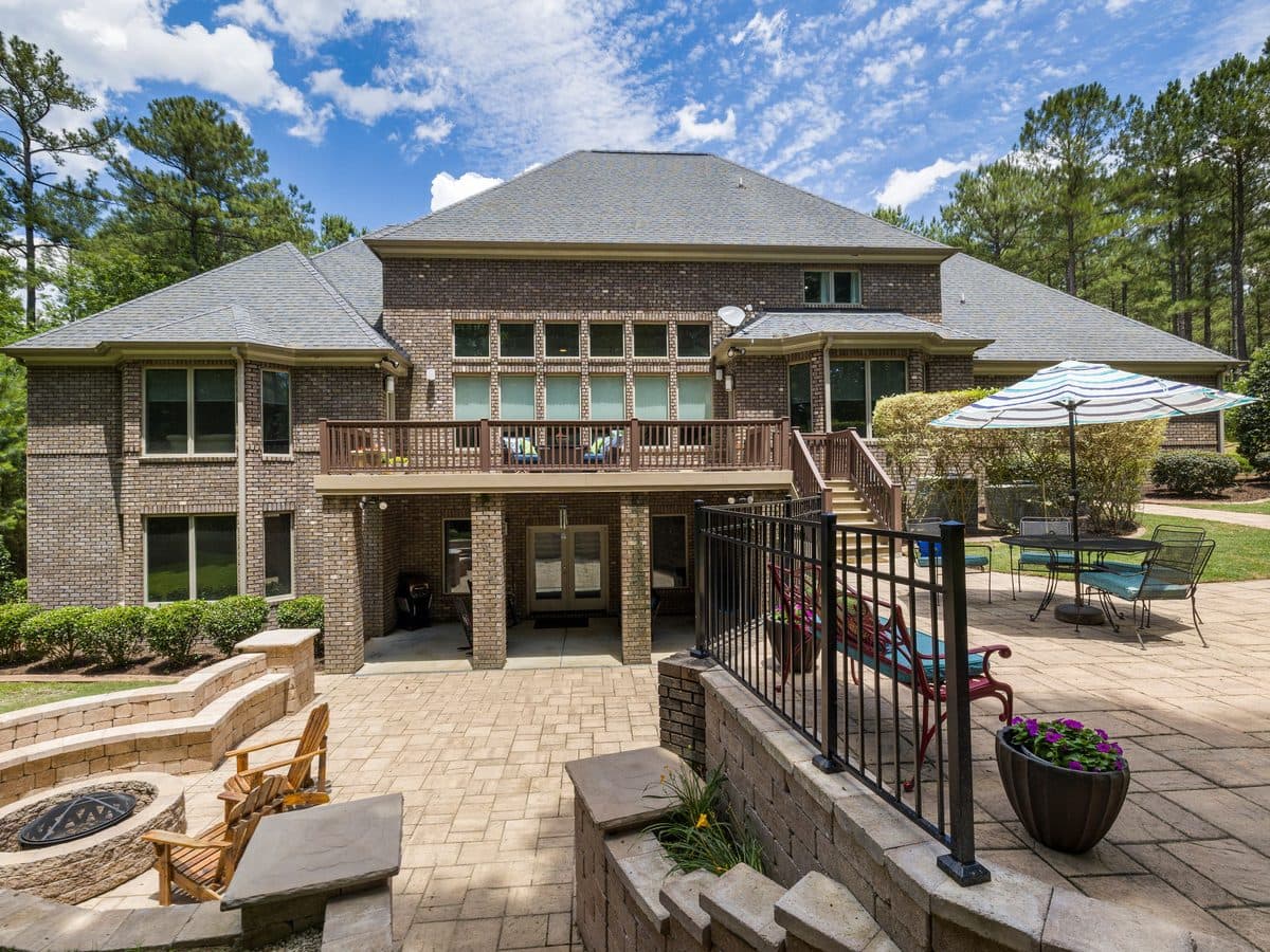 Large home with a multi-level paver terrace, seating area and mature landscaping