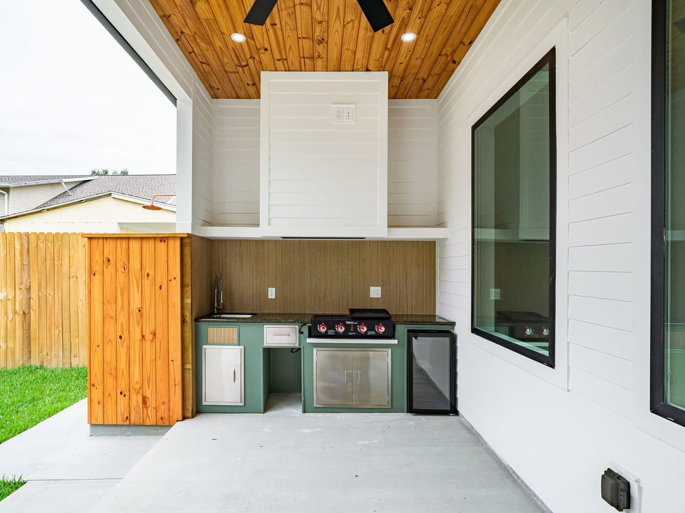 Built-in outdoor kitchen with stainless grill, cabinetry and a covered bar counter