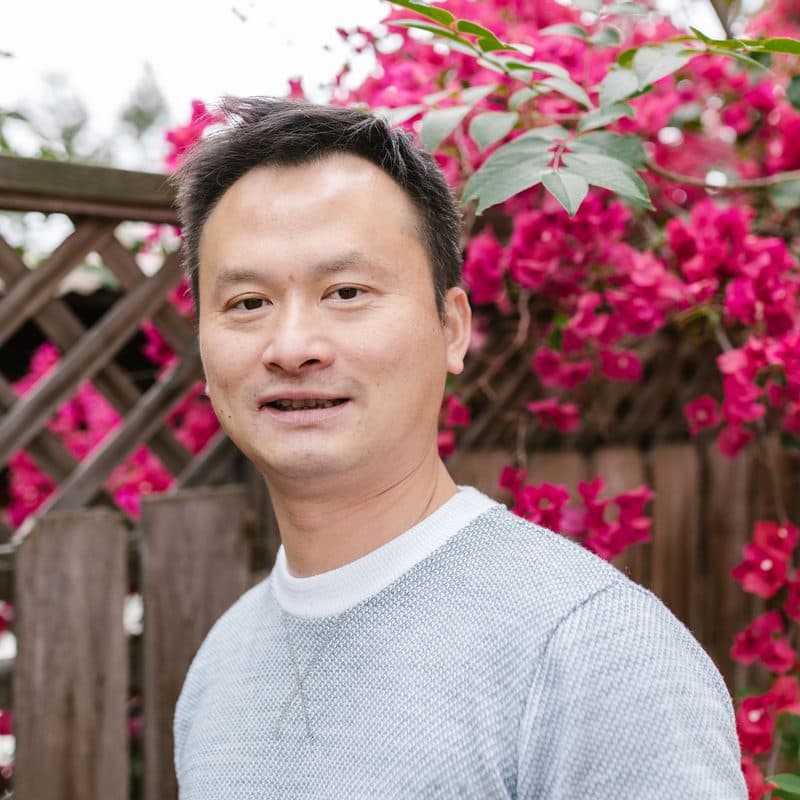 Kevin Trinh, irrigation manager, outdoors in front of flowering shrubs